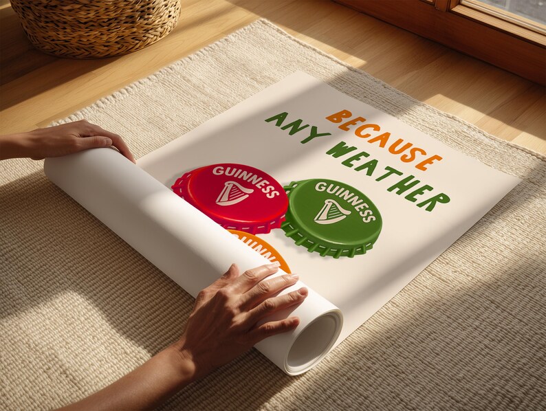 May include: A rolled-up poster featuring a red and green Guinness bottle cap design with the text "BECAUSE ANY WEATHER". The poster is on a beige rug, with a wicker basket in the background.