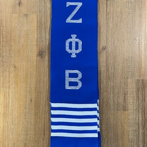 May include: Blue and white striped scarf with the letters Z, Phi, and B embroidered in white.