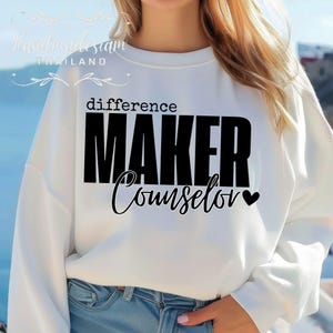 May include: White sweatshirt with black text that reads "difference maker counselor" with a small heart symbol.