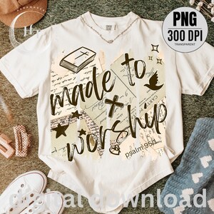 May include: Cream-colored t-shirt with the words "made to worship" in a handwritten style. The design includes a cross, stars, a dove, and a book. The text "psalm 95:1" is also visible.