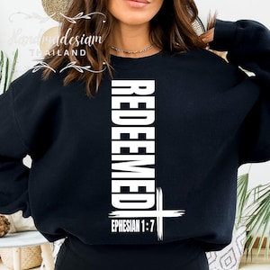 May include: Black sweatshirt with the word "REDEEMED" printed vertically in white, with a white cross and the text "EPHESIAN 1:7" below.