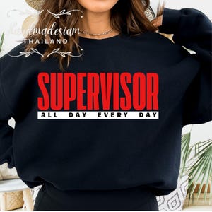 Puede incluir: Sudadera negra con el texto "SUPERVISOR ALL DAY EVERY DAY" en letras rojas.