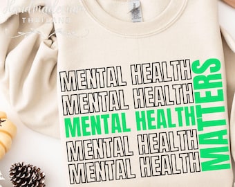 May include: A beige sweatshirt with the text "MENTAL HEALTH MATTERS" printed in black and green. The text "MENTAL HEALTH" is repeated five times in black, with the word "MATTERS" in green stacked vertically on the right side.