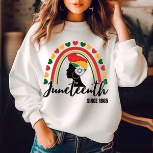 Könnte beinhalten: Weißes Sweatshirt mit einer schwarzen Silhouette einer Frau, die einen rot-gelb-grünen Kopftuch trägt. Die Frau steht vor einem Regenbogen aus Herzen in Rot, Gelb, Grün und Weiß. Der Text "Juneteenth Since 1865" ist unter dem Regenbogen gedruckt.