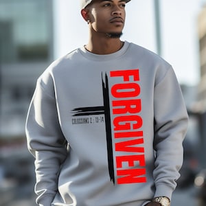 May include: A gray sweatshirt with a black cross and the word "FORGIVEN" in red lettering. The text "Colossians 2: 13-14" is printed below the cross.