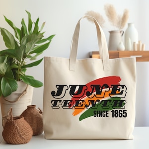 May include: A white canvas tote bag with a colourful graphic design that says "Juneteenth Since 1865".