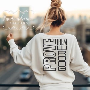 May include: White sweatshirt with the text "PROVE THEM WRONG" printed vertically in black on the back.