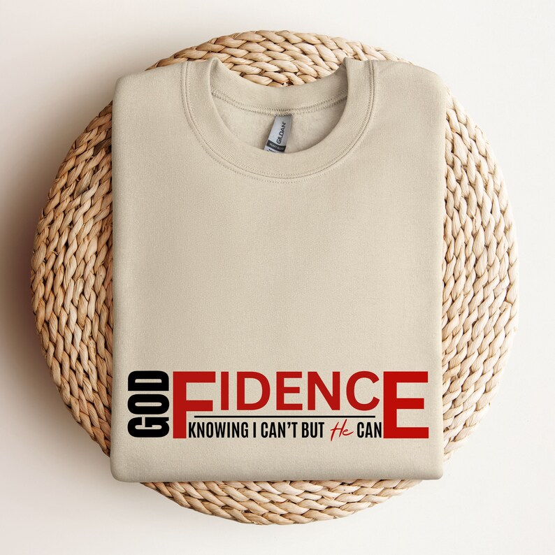 May include: Beige sweatshirt with the text "GOD FIDENCE" in red and black. The text continues with "KNOWING I CAN'T BUT He CAN".