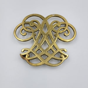 May include: A gold-colored metal ornament with a decorative, intricate design. The ornament is shaped like a heart with a lattice pattern in the center.