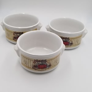 May include: Three white ceramic soup bowls with handles. Each bowl has a cream-colored band with the words "Campbell's Soup" and a red tomato illustration. The bowls are empty and ready for use.