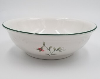 May include: A white ceramic bowl featuring a dark green rim and a delicate botanical illustration on the exterior. The design depicts a sprig with muted green leaves and small red berries, centred on the smooth, rounded side of the bowl.