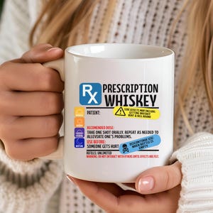 Puede incluir: Una taza de cer&aacute;mica blanca con un dise&ntilde;o gr&aacute;fico que imita una etiqueta de receta m&eacute;dica con el texto Prescription Whiskey. El dise&ntilde;o incluye un s&iacute;mbolo Rx, instrucciones de dosificaci&oacute;n y etiquetas de advertencia en amarillo y azul.