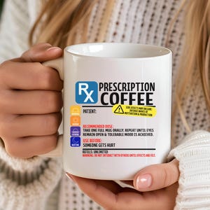 Puede incluir: Una taza de cer&aacute;mica blanca con un gr&aacute;fico de etiqueta de receta m&eacute;dica que incluye el texto Prescription Coffee, el s&iacute;mbolo Rx e instrucciones de uso, incluyendo dosis recomendada, efectos secundarios e informaci&oacute;n de recarga en negro, azul y amarillo.