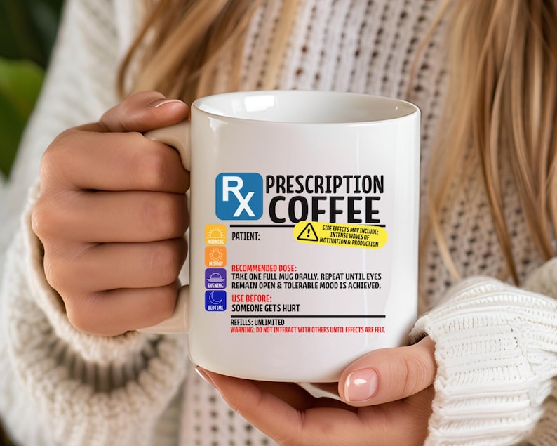 Puede incluir: Una taza de cer&aacute;mica blanca con un gr&aacute;fico de etiqueta de receta m&eacute;dica que incluye el texto Prescription Coffee, el s&iacute;mbolo Rx e instrucciones de uso, incluyendo dosis recomendada, efectos secundarios e informaci&oacute;n de recarga en negro, azul y amarillo.