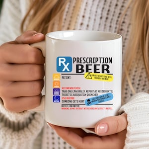 Puede incluir: Una taza de cer&aacute;mica blanca con un dise&ntilde;o gr&aacute;fico que imita una etiqueta de receta m&eacute;dica, con el texto Prescription Beer, el s&iacute;mbolo Rx, instrucciones de dosis y advertencias en azul, amarillo y rojo sobre un fondo blanco.