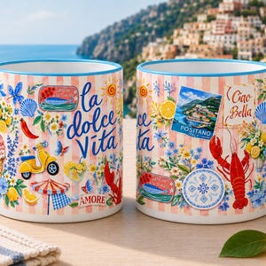 May include: Two ceramic mugs with blue handles and rims. The mugs feature a design with Italian imagery, including a yellow scooter, lobster, and the words "la dolce Vita" and "Ciao Bella". The background is a light pink and white striped pattern.