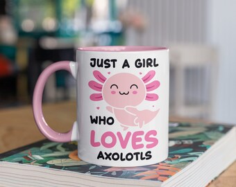 Puede incluir: Taza de cerámica blanca con interior y asa rosas. La taza presenta el texto "JUST A GIRL WHO LOVES AXOLOTLS" y una ilustración de ajolote rosa. La taza está sobre un libro.