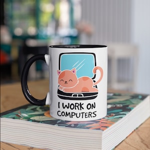Pode incluir: Caneca de cerâmica branca com borda e alça pretas. A caneca apresenta um gato de desenho animado dormindo em um laptop com o texto "Trabalho em computadores".