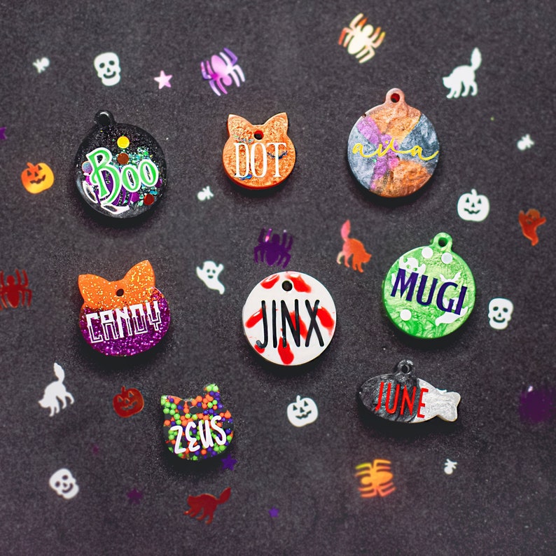 May include: Nine Halloween-themed pet ID tags with various colors, patterns, and names including Boo, Dot, Candy, Jinx, Mugi, June, and Zeus.