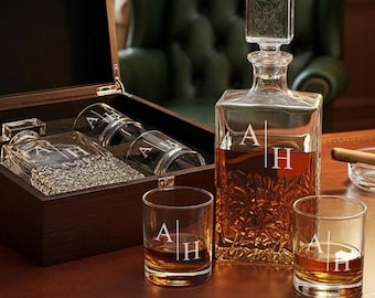 Pode incluir: Um conjunto de decantador de whisky personalizado com uma caixa de madeira. O conjunto inclui um decantador quadrado com rolha, dois copos de whisky e uma caixa de madeira. O decantador e os copos são gravados com as iniciais "A H".
