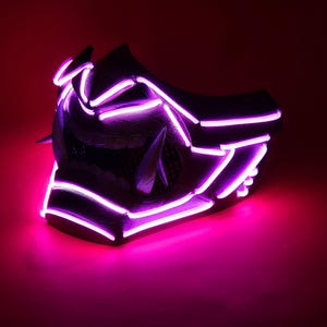 Può includere: Una maschera futuristica con luci al neon viola brillante. La maschera è nera con angoli acuti e un design minaccioso. Le luci al neon delineano le caratteristiche della maschera, creando un effetto visivo sorprendente sullo sfondo rosso scuro.