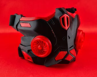 May include: A black and red 3D printed mask with a futuristic design. The mask has two red vents on the sides and a red detail on the front.