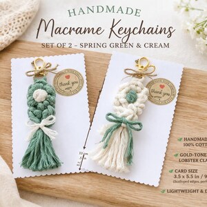 Peut inclure: Deux porte-clés macramé faits à la main, un vert printemps et un crème, présentés sur des cartes blanches. Chaque porte-clés présente un motif floral, une gland et un fermoir mousqueton doré. Les cartes ont un bord festonné et un autocollant "merci". Le texte indique "Macramé Keychains FAIT MAIN".