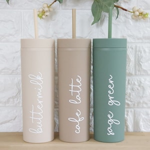 May include: Three tall, reusable tumblers with straws. The tumblers are in shades of beige, brown, and green. The tumblers are labeled "buttermilk", "cafe latte", and "sage green".