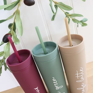 May include: Three reusable tumblers with matching straws. The tumblers are in shades of burgundy, green, and beige. The tumblers have white text that reads "my mix", "soft green", and "cafe latte".