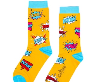 May include: A pair of yellow comic book-themed socks with blue accents. The socks feature various comic book exclamations like "OMG!", "BOOM!", and "POW!" in colorful speech bubbles. The brand name "ALTER SOCKS" is printed on the side.