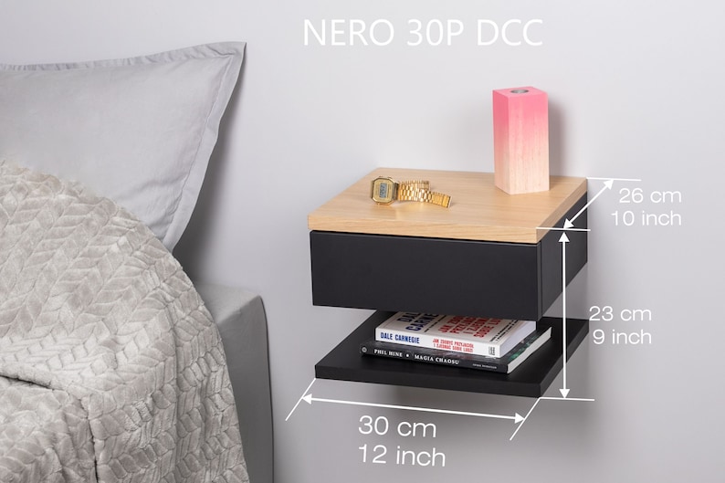 May include: Black floating nightstand with a drawer and a shelf. The nightstand has a wood top and measures 30 cm wide, 26 cm deep, and 23 cm tall.