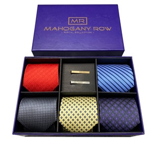 May include: A purple box with the text "MR MAHOGANY ROW - ROYAL COLLECTION -" on the lid. The box contains six ties in a variety of colors and patterns, including red, blue, yellow, and gray. Two tie clips are also included in the box.
