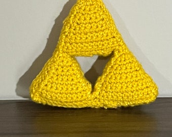 May include: A yellow crocheted triangular pillow with a smaller triangle cut out of the center, resembling the Triforce symbol from the Legend of Zelda video game series.
