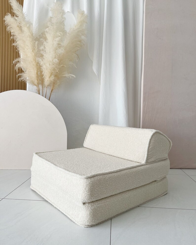 May include: A white, fluffy, foldable chair with a rounded back. The chair is made of a soft, plush fabric and is perfect for lounging or sleeping.