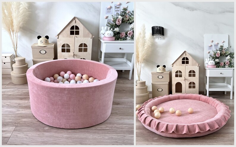 May include: A pink velvet ball pit with a ruffled edge and white and pink balls inside. The pit is sitting on a wooden floor.