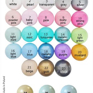 May include: Chart of 26 different colored beads, numbered 1 through 26. The beads are arranged in rows of five, with the numbers and names of the colors written below each bead. The colors include white, pearl, transparent, gray, silver, powder pink, baby pink, pink, dusty pink, strong pink, light mint, mint, turquoise, metallic turquoise, light green, light blue, blue, metallic navy, purple, mustard, beige, gold, black, metallic beige, metallic light mint, and metallic light blue.