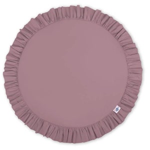 Puede incluir: Una alfombra de juego redonda de color malva con un borde con volantes. La alfombra est&aacute; hecha de tela suave y c&oacute;moda, ideal para beb&eacute;s y ni&ntilde;os peque&ntilde;os.