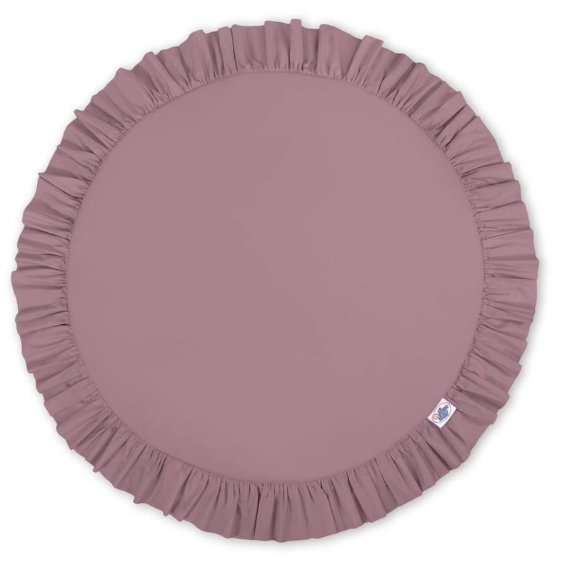 Puede incluir: Una alfombra de juego redonda de color malva con un borde con volantes. La alfombra est&aacute; hecha de tela suave y c&oacute;moda, ideal para beb&eacute;s y ni&ntilde;os peque&ntilde;os.