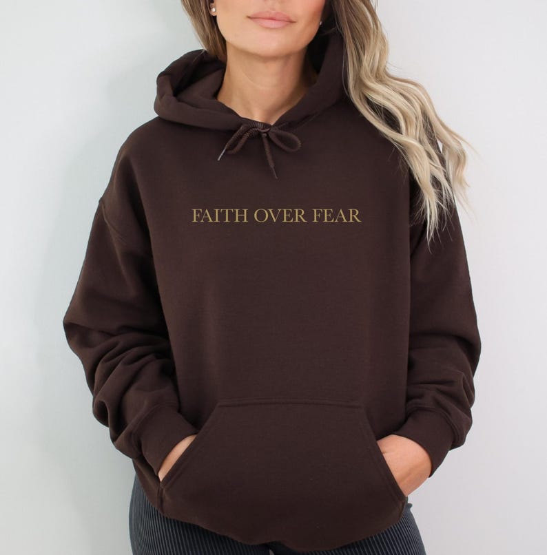 May include: A brown hooded sweatshirt with the text "FAITH OVER FEAR" printed in gold on the front.
