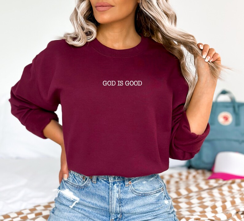 May include: A maroon sweatshirt with the text "GOD IS GOOD" embroidered in white on the front.