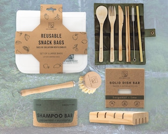 May include: A set of zero waste products including reusable snack bags, a bamboo utensil set, a shampoo bar, a dish soap bar, and a wooden dish brush. The products are arranged on a green and brown background.
