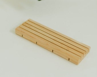 May include: A wooden soap dish with five slots for bar soap. The dish is made of light brown wood and has a natural finish.