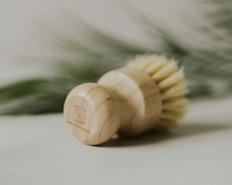 May include: A close-up of a wooden brush with natural bristles. The brush has a wooden handle with a small square logo that says "Save Our Planet".