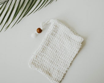May include: A white mesh laundry bag with a wooden toggle closure. The bag is made of a fine, delicate mesh and is perfect for washing delicates.