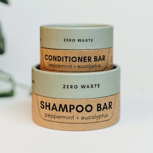 May include: Two zero waste bars, one labelled "Shampoo Bar" and the other "Conditioner Bar", both with the scent "peppermint + eucalyptus".