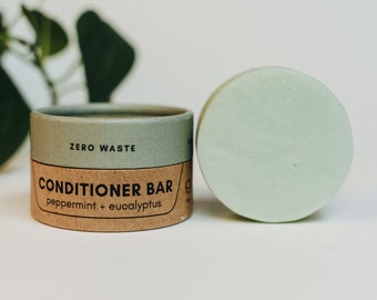 May include: A round, light green conditioner bar in a cardboard tube with the text "ZERO WASTE CONDITIONER BAR peppermint + eucalyptus" printed on it.