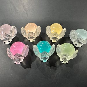 May include: Seven glass figurines of ladybugs in various pastel colors. Each ladybug has a clear glass body with a translucent colored dome and black eyes.