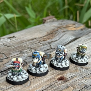 Puede incluir: Cuatro figuras en miniatura de carlinos con atuendos de estilo militar. Cada carlino está sobre una base de calaveras. Los carlinos están pintados con detalles, incluyendo cascos y mochilas.