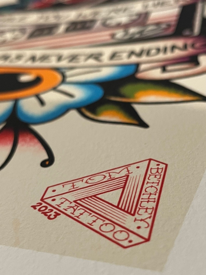 May include: Red triangle logo with the text "Tom Beichley Tattoo" and the year "2023" printed on a white background.