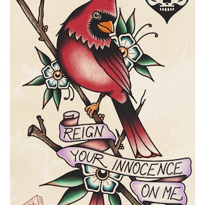 May include: A traditional tattoo style illustration of a red cardinal perched on a branch with green leaves and blue flowers. A purple ribbon with the text "Reign Your Innocence On Me" is wrapped around the branch. A black and white skull heart is in the top right corner. The artist's signature "Tom Beghley Tattoo 2022" is in the bottom left corner.